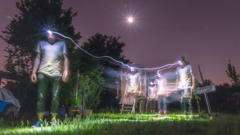 Students walking at night with headlamps looking in grass