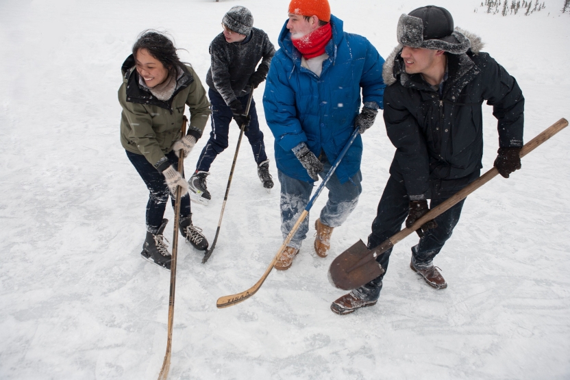 Students play hockey on the ice with hockey sticks and shovels
