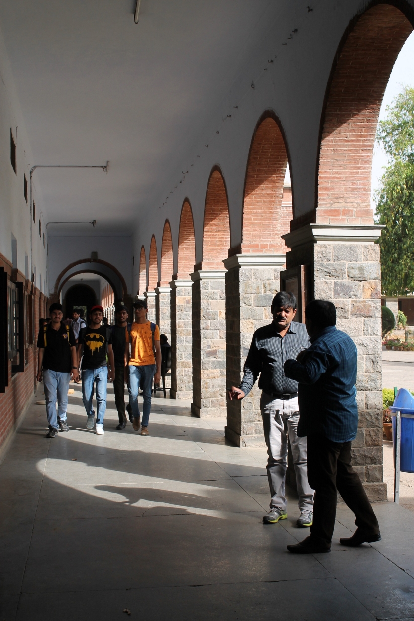 Students and professors talk and walk on a corridor of a college building