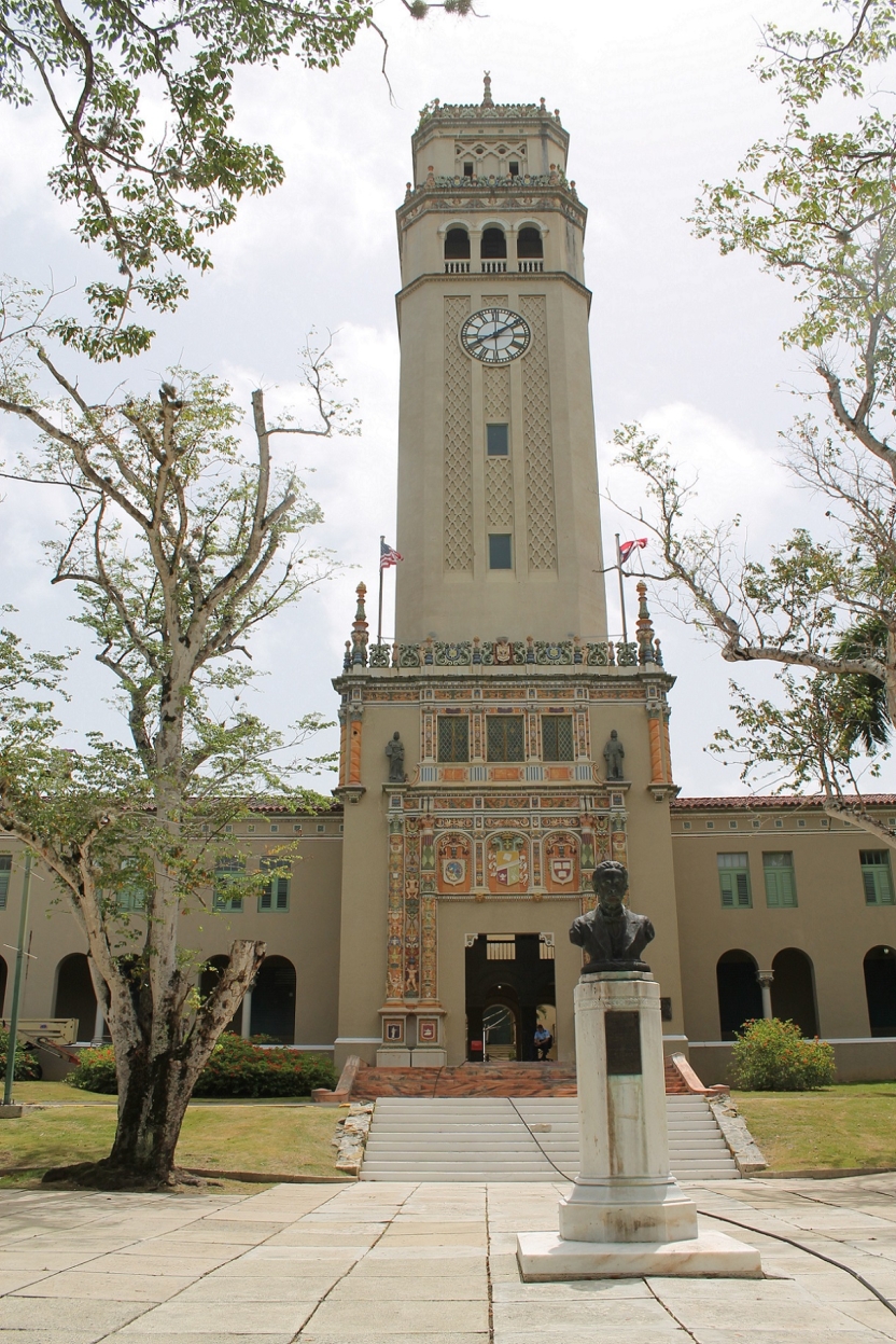 A bell tower with a statue in front