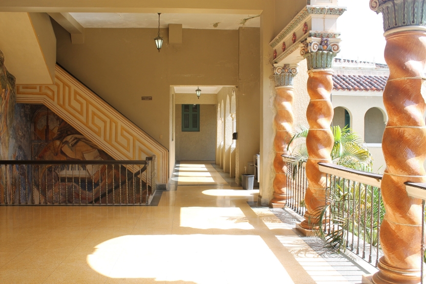 A sunny hallway with a mural and spiraling columns