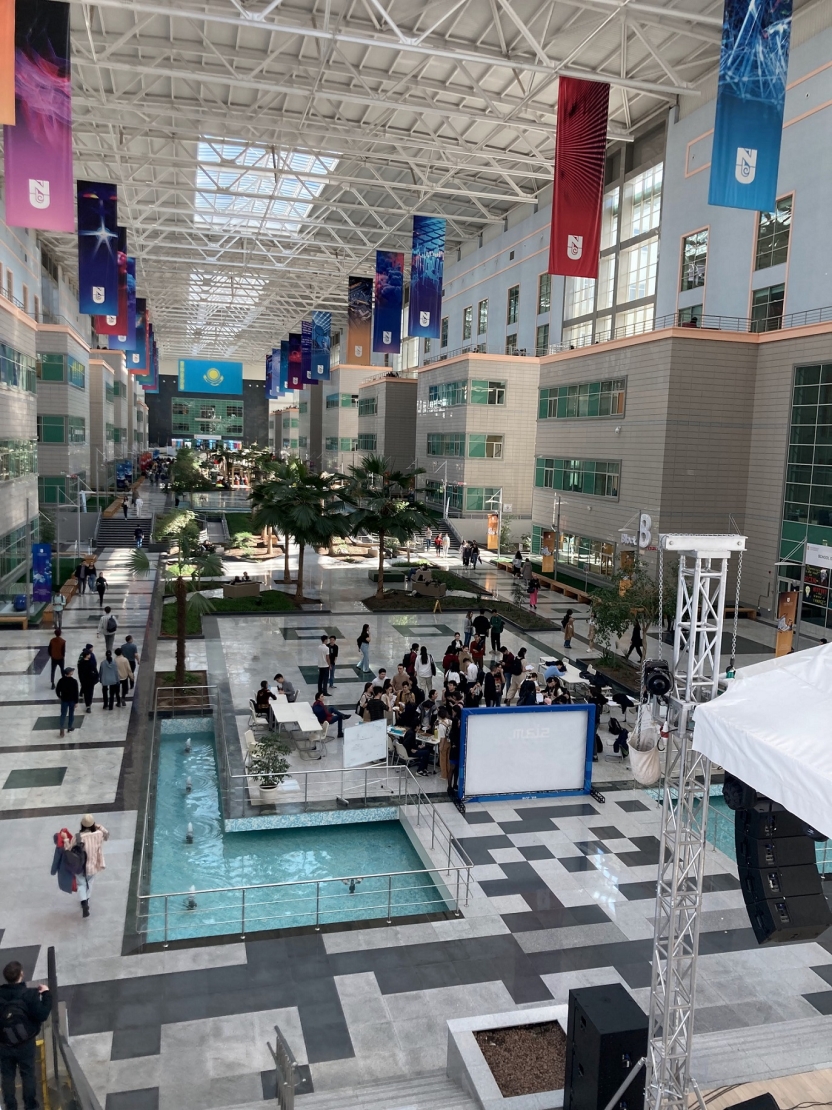 A university atrium with flags, fountains, and greenery