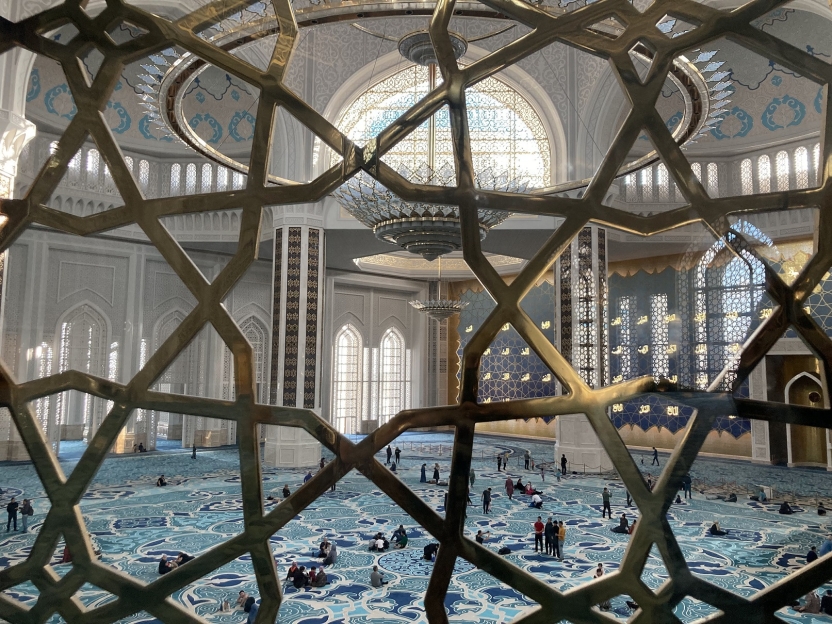 The inside of a large mosque with lattice in the foreground