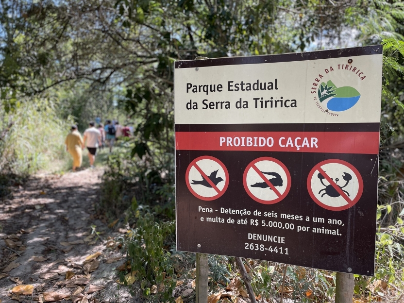 A sign in the state park with students walking along a trail in the background