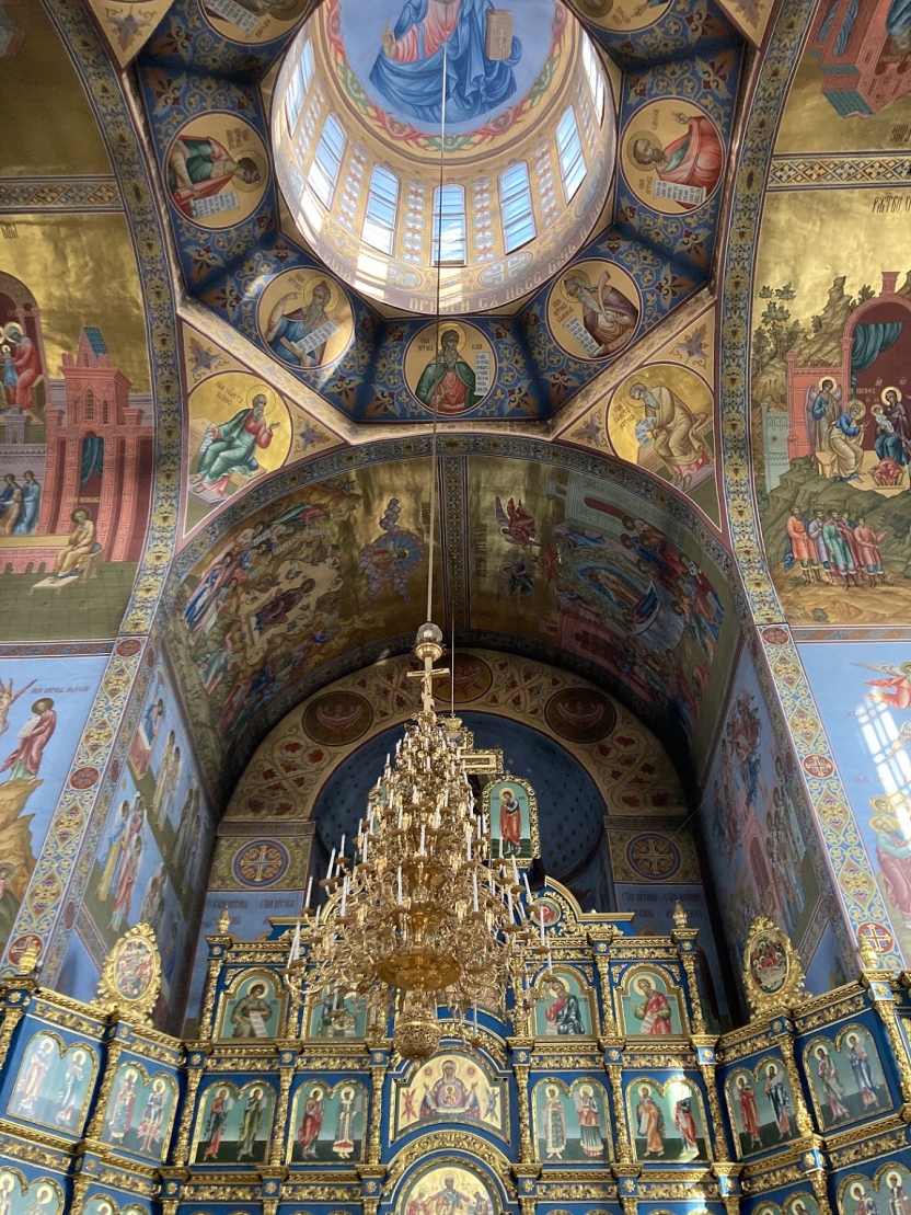 The inside of a cathedral with frescoes and a chandelier