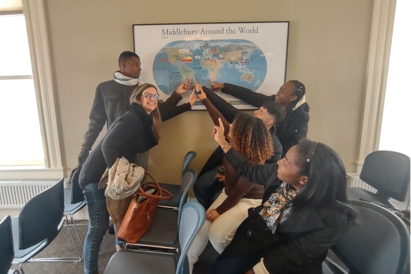 Students pointing to Brazil on a world map reading "Middlebury Around the World"