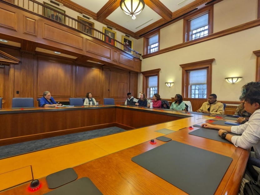 Students at a conference table with President Laurie Patton