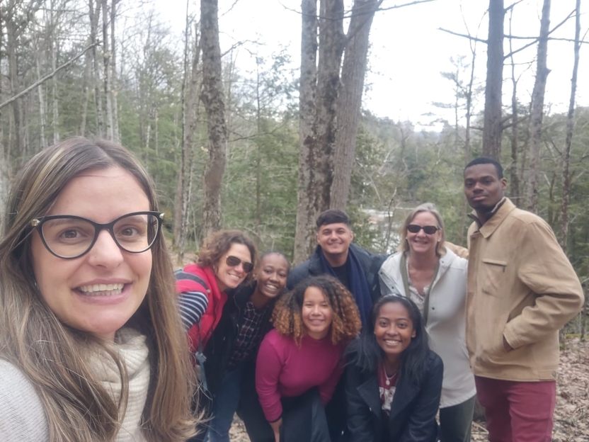 Students and staff in the woods near a body of water