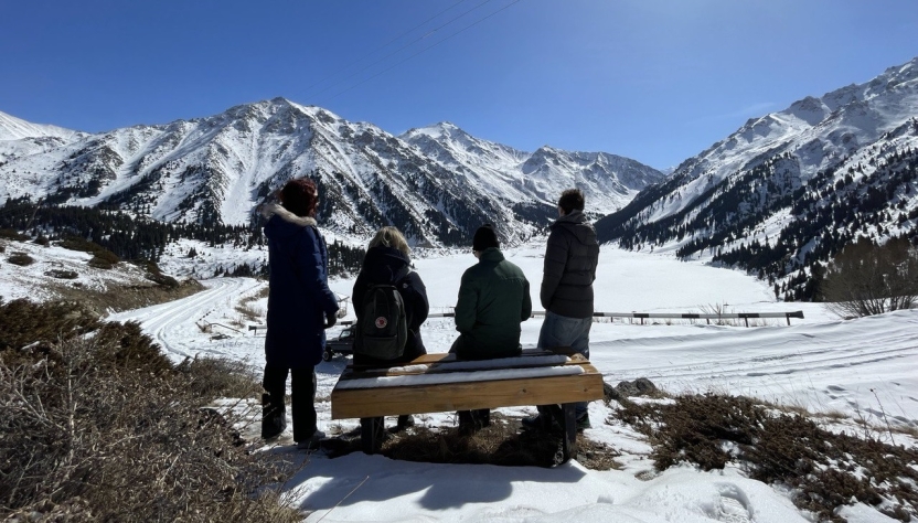 Four people with their backs turned, looking at the mountains in the snow