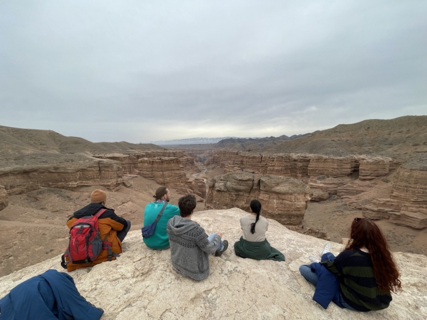 Four people sitting near the edge of a canyon, looking out