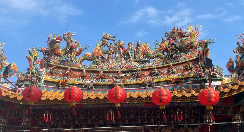 The top of a decoratively carved building with lanterns in the foreground