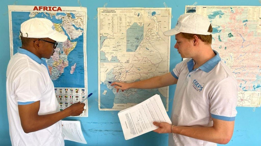 Two students standing by a map.