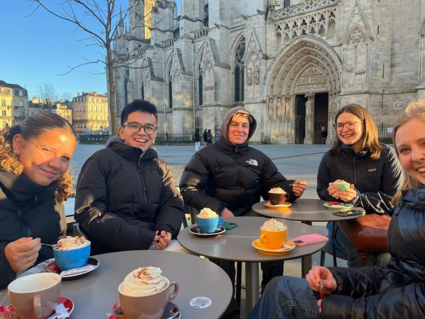 Students sitting in an outdoor square drinking cocoa