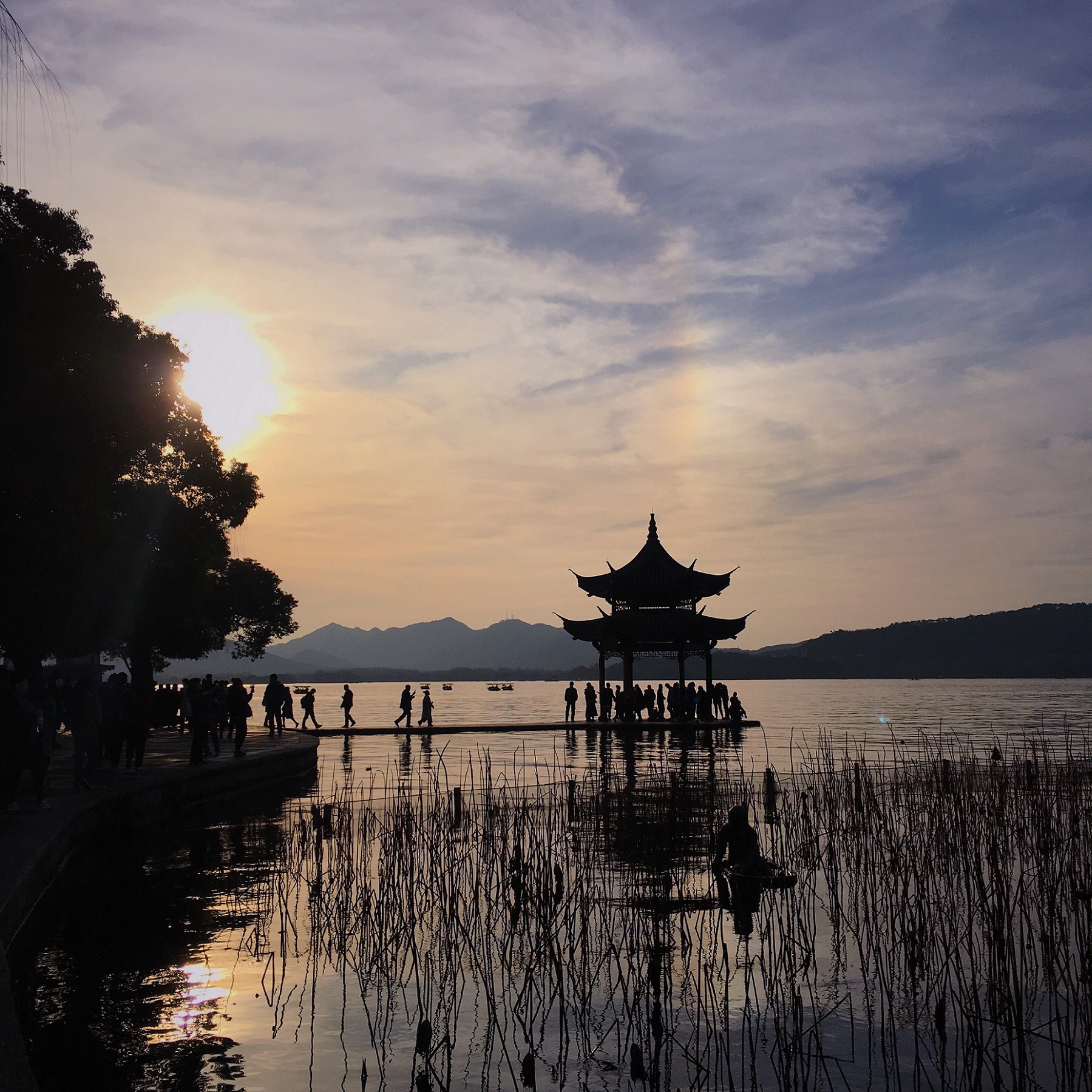At sunset, people walk to a gazebo in the lake