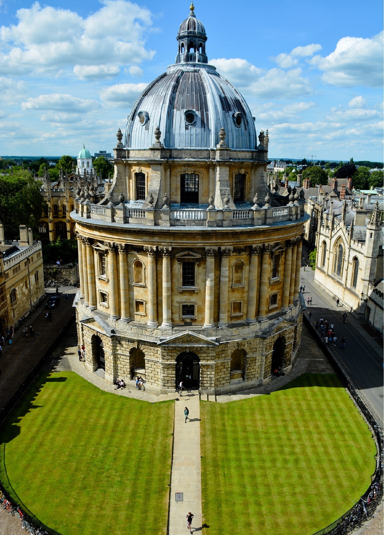 A round university building with a dome with a grassy lawn in front