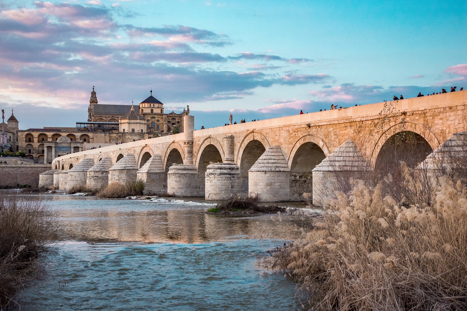 An old bridge over a river, in front of a cathedral