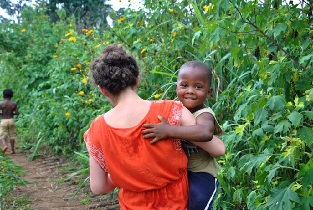 Student carrying her host brother in the fields of Cameroon.