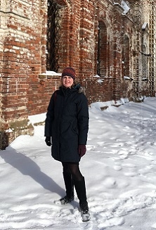 A student stands in the snow in front of an old brick building