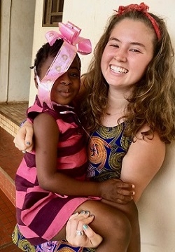 A student holds her host sister, a small child