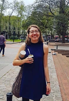 A student stands in a plaza holding a mate gourd.