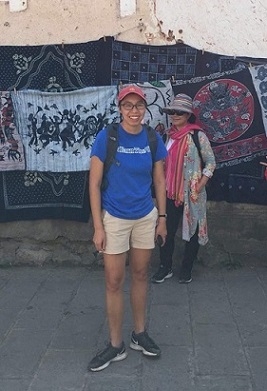 A student stands with tapestries behind her