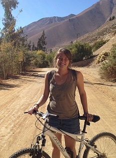 A student stands with a bicycle on a dirt road