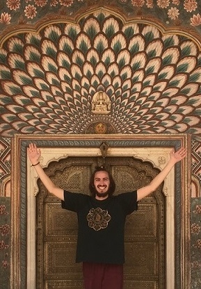 A student stands in a decorated doorway, arms outstretched