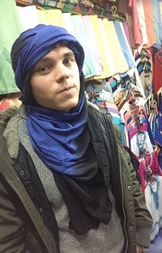 A student in the marketplace with a traditionally wrapped scarf on his head