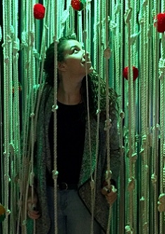 A student stands among lengths of rope in a green-lit room