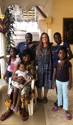 A student stands with her host family, dressed in Cameroonian clothing