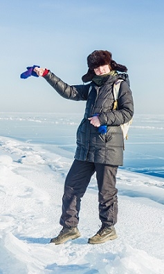 A student stands on the ice in front of a lake