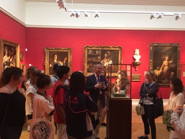 Students gather around a man next to a small statue at the Ashmolean Museum