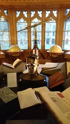 Globes, books, a telescope, and a bust on display