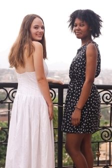 Two students in dresses looking back at the camera and smiling