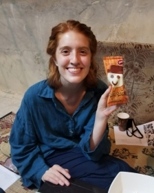 A student smiling and holding up a package with a smiling figure on it