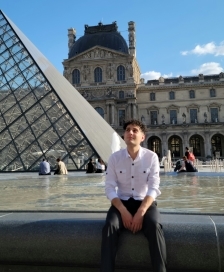 Student sitting in front of the Louvre's glass pyramid