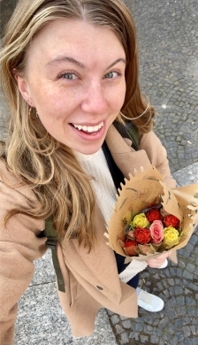 A student smiling holding a bouquet 