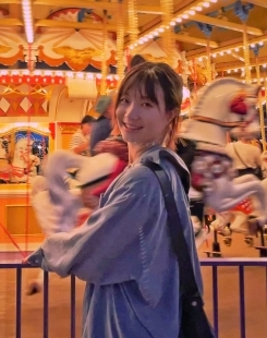 Student smiling in front of a glowing carousel 