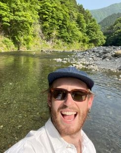 Student smiling with a river and mountains in the background