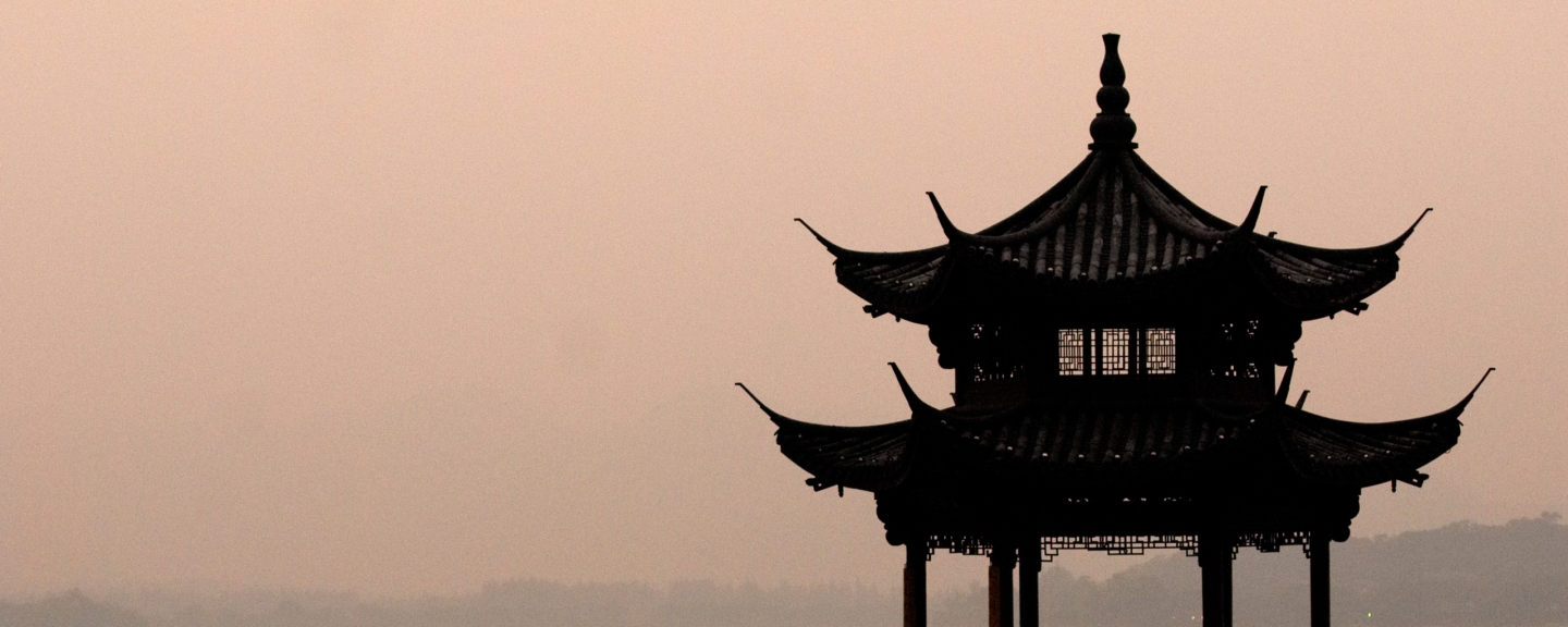 Top of pagoda with hazy, peach-colored sky in background