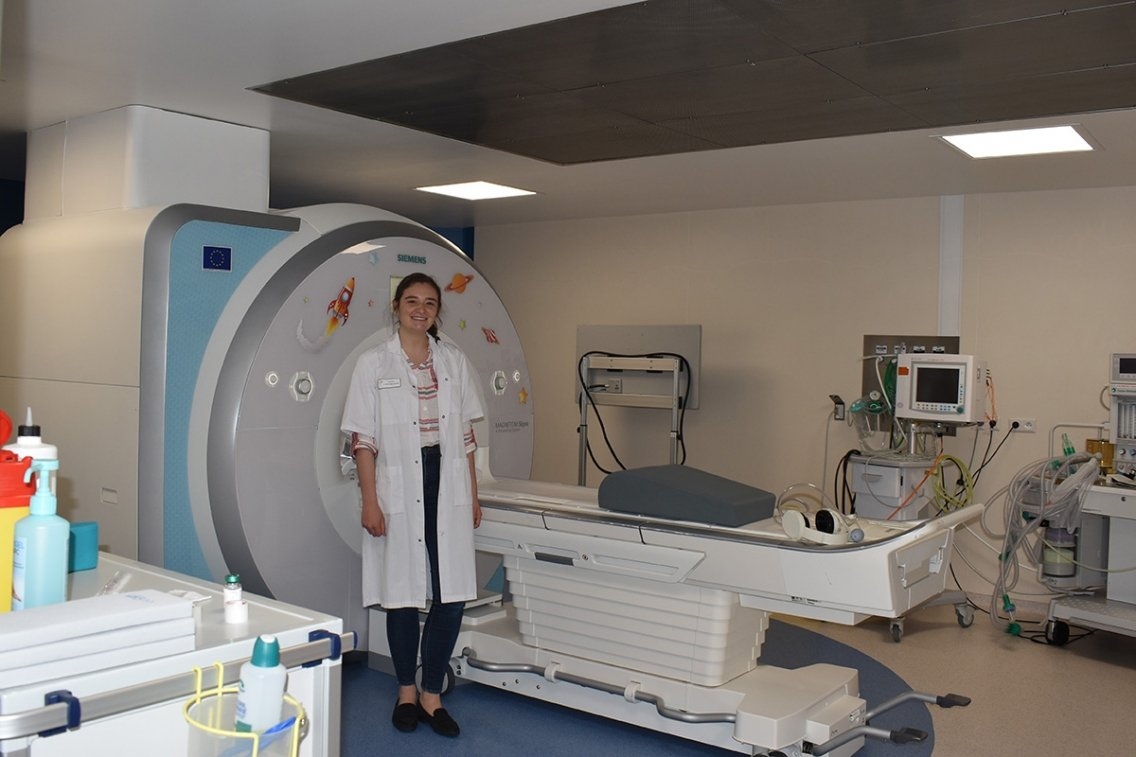 A student stands in a lab in front of a CT scanner