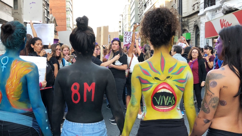 Backs of female student protesters wearing body paint