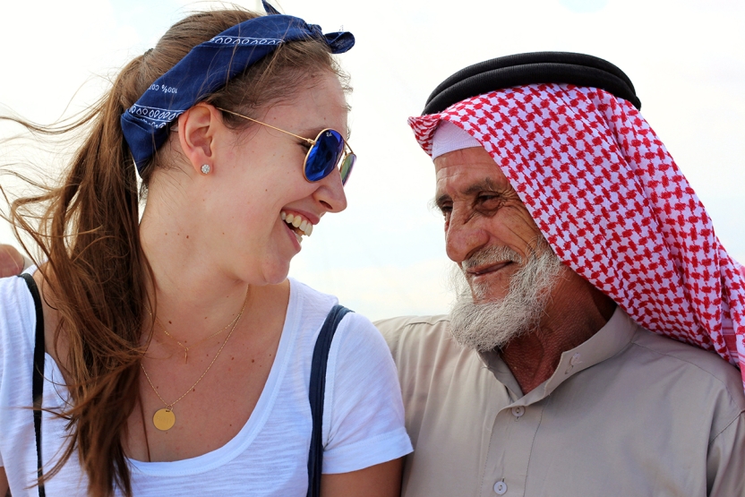 Photo of student with elderly Jordanian man, smiling at each other.