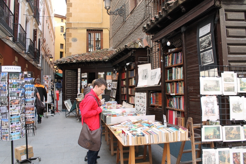 A student looks at books on a stand in the street