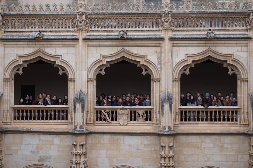 A large group of students look out from the archways of a building