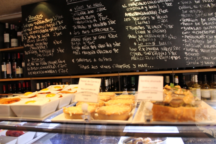 Small portions of food, with a menu on the wall behind