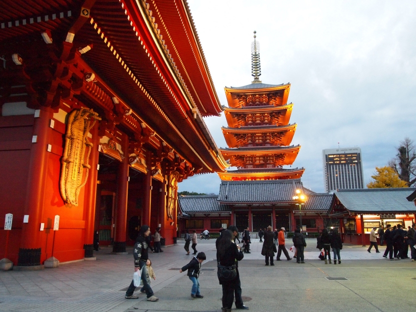 A family walks past a temple, lit up in the evening