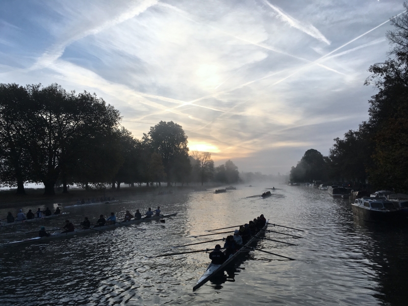 A boat with students rowing on the river at dawn