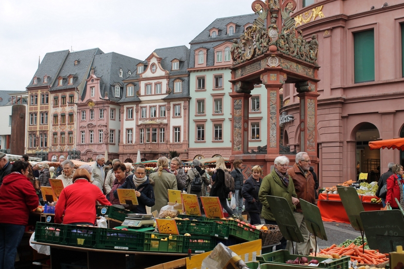 People in a busy marketplace shopping for vegetables