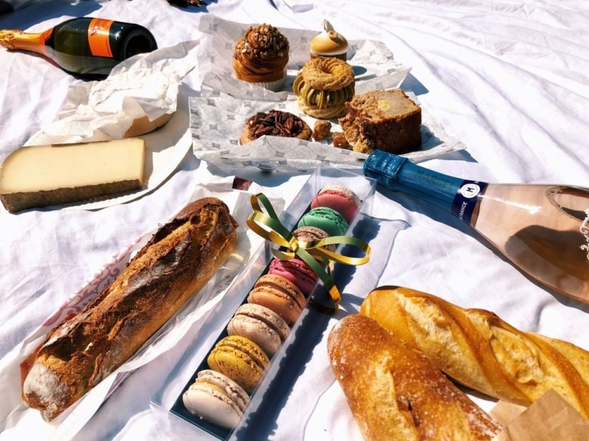 Sweets, bread, and wines laid out on a blanket
